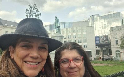 Cityscape with people, historic and modern buildings, and a cloudy sky.